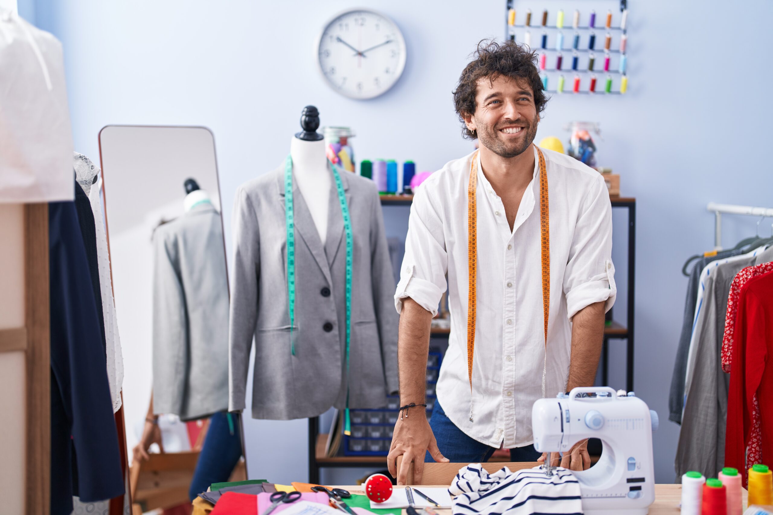 Young hispanic man tailor smiling confident standing at clothing factory